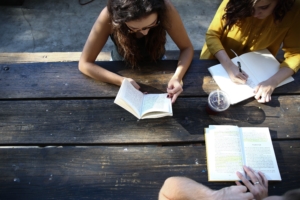 Group of three people talking with open books in front of them.